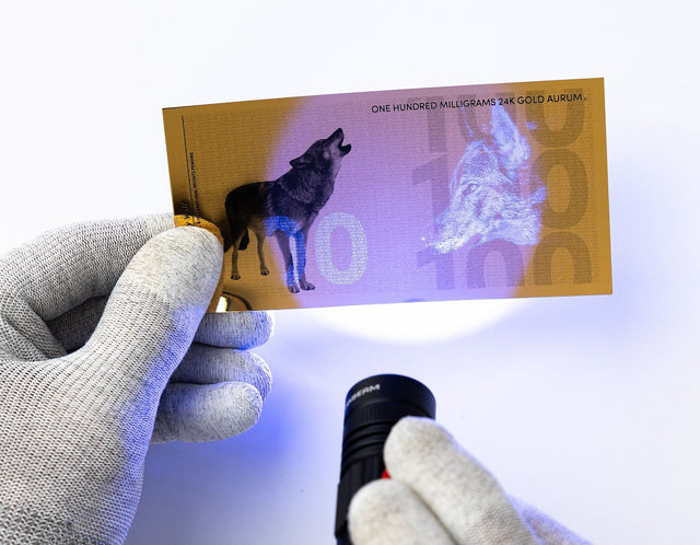 100 milligram 24k gold bill shown with uv security features under black light